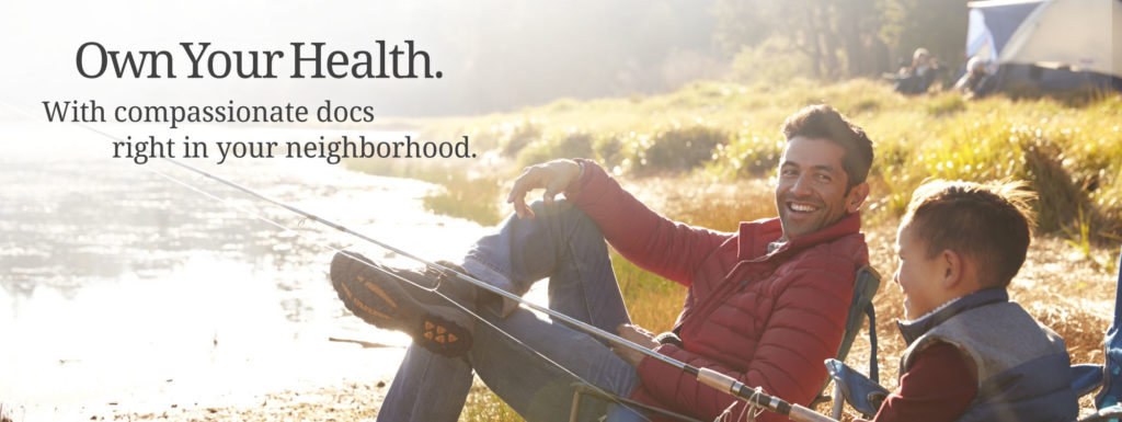 Image of father and son sitting by a river camping and fishing. Overlay text reads "Own Your Health. With compassionate docs right in your neighborhood."